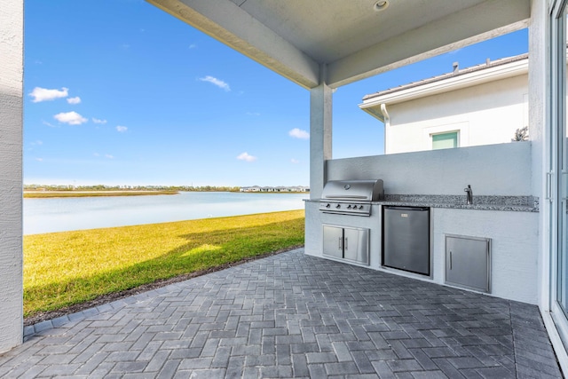 view of patio / terrace with a water view, exterior kitchen, sink, and grilling area