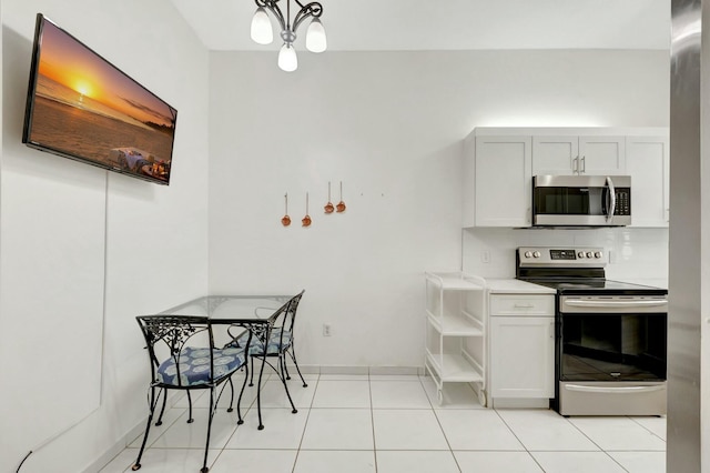 kitchen featuring baseboards, decorative light fixtures, light countertops, light tile patterned flooring, and stainless steel appliances