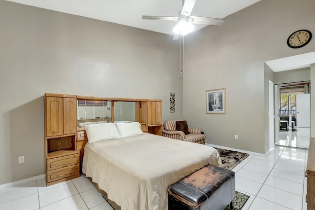 bedroom featuring light tile patterned floors, a ceiling fan, baseboards, and a towering ceiling