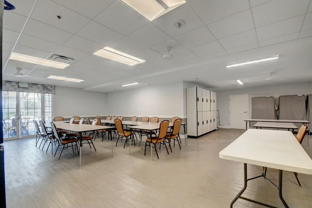 dining area with light wood finished floors, visible vents, and a drop ceiling