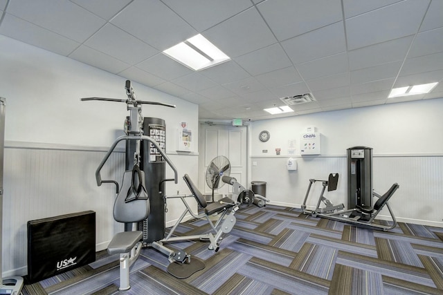 workout area with a drop ceiling, visible vents, a wainscoted wall, and carpet floors