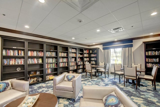 living area featuring visible vents, carpet floors, ornamental molding, and bookshelves