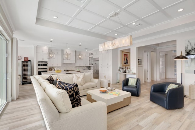 living room with ornamental molding, coffered ceiling, and light wood-type flooring