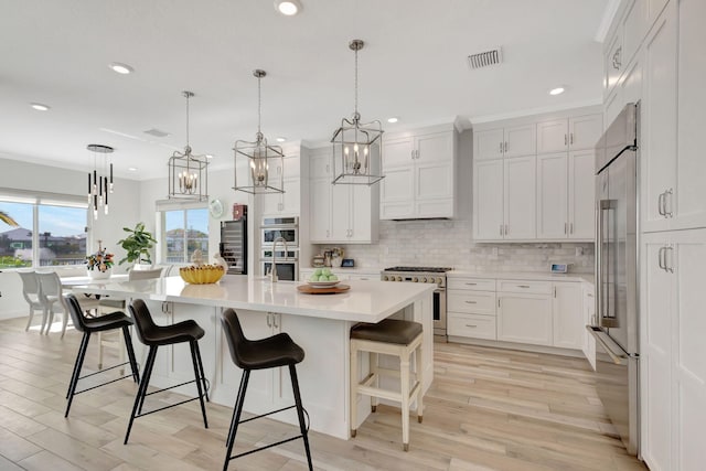 kitchen featuring a spacious island, high end appliances, white cabinetry, and light wood-type flooring