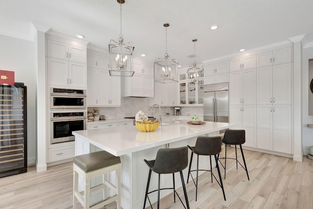 kitchen featuring a kitchen breakfast bar, white cabinets, a spacious island, and appliances with stainless steel finishes