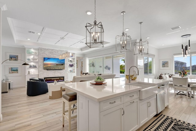 kitchen featuring a center island with sink, light hardwood / wood-style floors, a stone fireplace, and sink