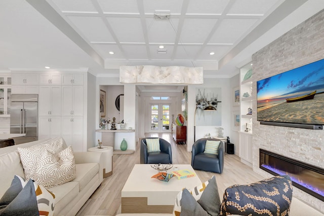 living room featuring french doors, coffered ceiling, a stone fireplace, light hardwood / wood-style floors, and ornamental molding