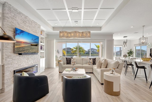 living room with a fireplace, light wood-type flooring, a chandelier, and coffered ceiling