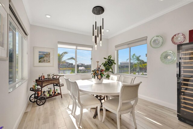 dining area featuring a notable chandelier, crown molding, wine cooler, and light hardwood / wood-style flooring