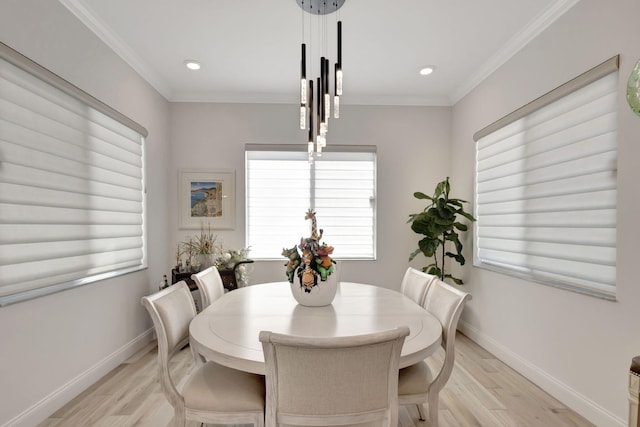 dining area with ornamental molding and light hardwood / wood-style flooring