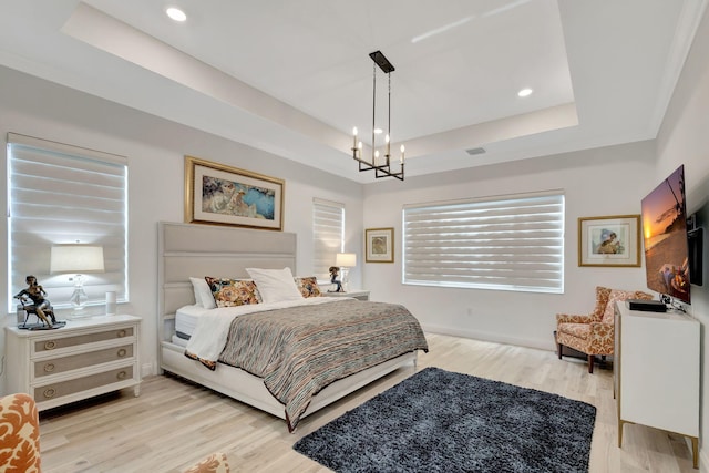 bedroom with light wood-type flooring, a raised ceiling, and a notable chandelier