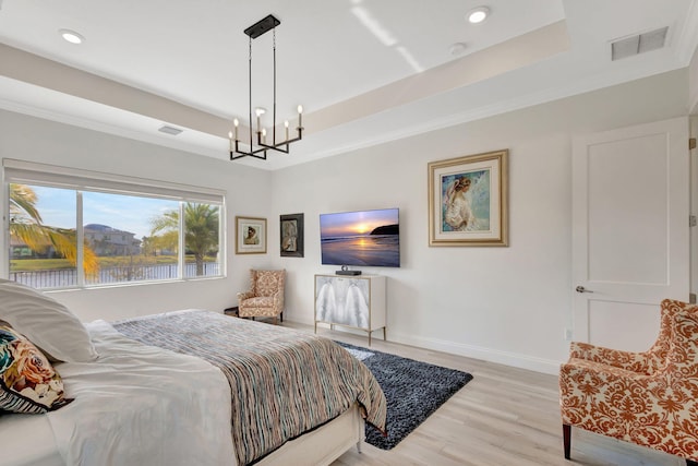 bedroom featuring light wood-type flooring, a tray ceiling, and a chandelier