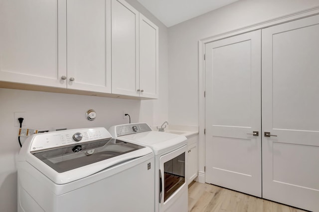 washroom with washing machine and clothes dryer, sink, cabinets, and light wood-type flooring