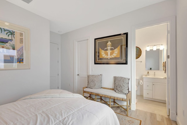 bedroom featuring ensuite bath, sink, and light hardwood / wood-style flooring