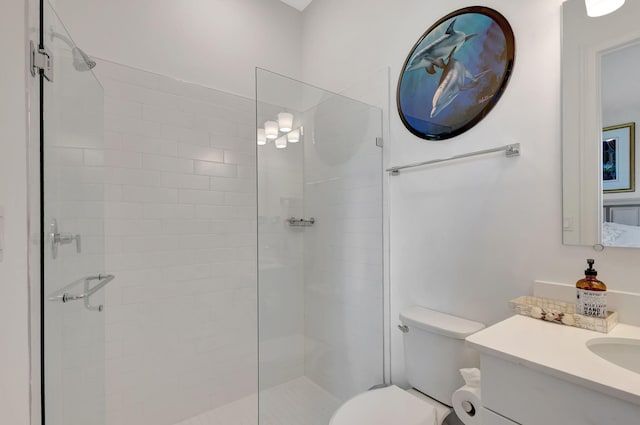 bathroom featuring a shower with door, vanity, and toilet