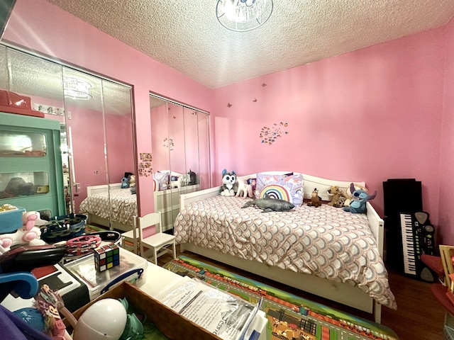 bedroom with hardwood / wood-style flooring, a textured ceiling, and multiple closets