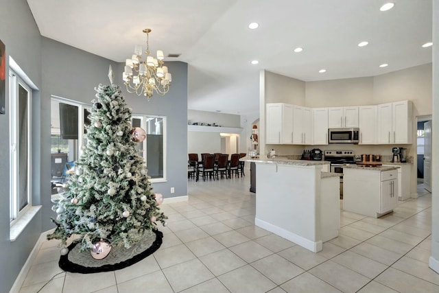 kitchen featuring white cabinets, decorative light fixtures, stainless steel appliances, and light tile patterned floors