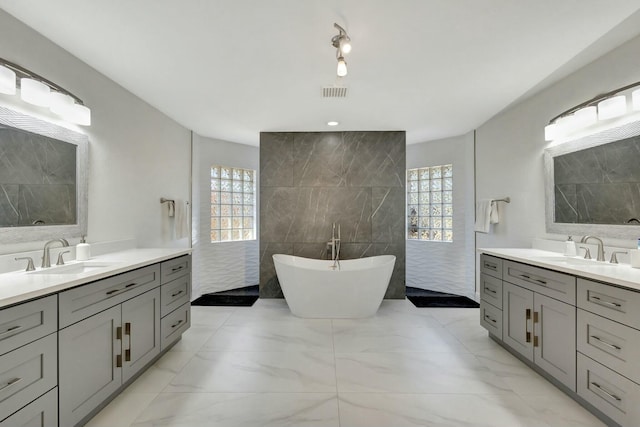 bathroom with vanity, plenty of natural light, a bathing tub, and tile walls