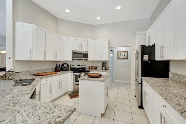 kitchen with a center island, white cabinetry, light stone countertops, and appliances with stainless steel finishes