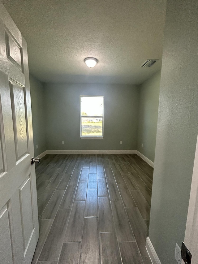 spare room featuring dark hardwood / wood-style floors and a textured ceiling