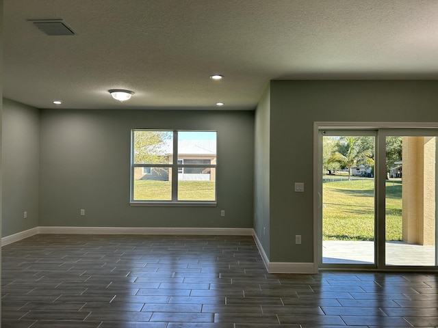 unfurnished room with dark hardwood / wood-style flooring and a textured ceiling