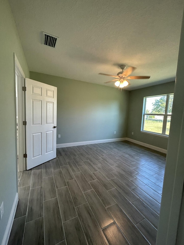 spare room featuring ceiling fan, dark wood-type flooring, and a textured ceiling