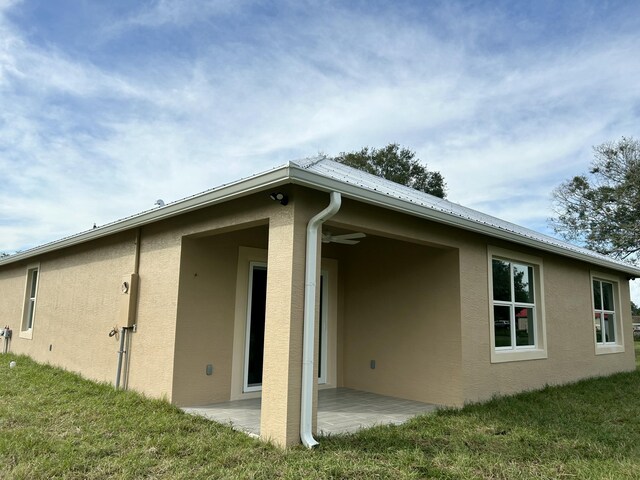 view of side of home featuring a patio area and a lawn