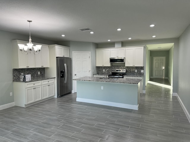 kitchen with white cabinets, appliances with stainless steel finishes, dark stone counters, and pendant lighting