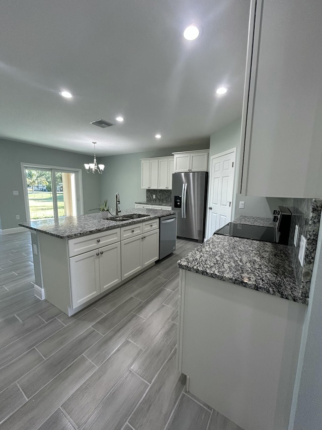 kitchen with sink, stainless steel appliances, light stone counters, pendant lighting, and white cabinets