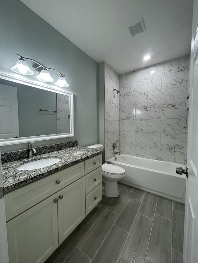 full bathroom with toilet, vanity, and tiled shower / bath