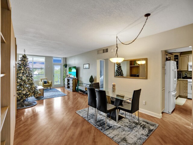 dining room with a textured ceiling and light hardwood / wood-style flooring