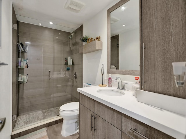 bathroom featuring hardwood / wood-style floors, vanity, a shower with shower door, and toilet