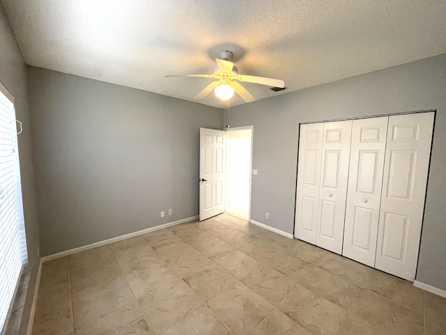 unfurnished bedroom with multiple windows, ceiling fan, a closet, and a textured ceiling