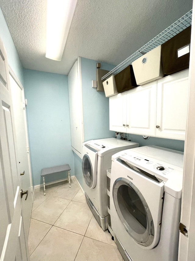 laundry room featuring independent washer and dryer, cabinets, a textured ceiling, and light tile patterned flooring