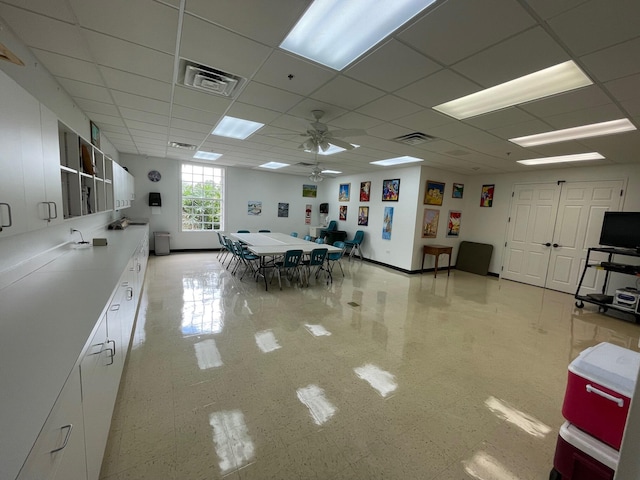 interior space with a drop ceiling and ceiling fan