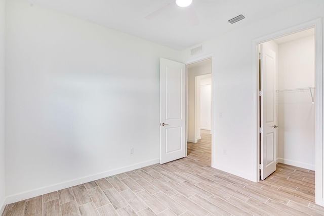 unfurnished bedroom featuring a closet, light hardwood / wood-style flooring, and ceiling fan