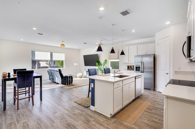 kitchen with white cabinetry, a center island with sink, stainless steel appliances, and sink