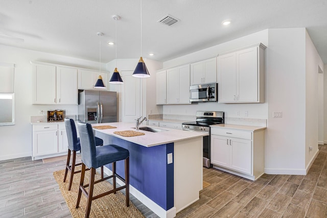 kitchen featuring pendant lighting, sink, white cabinets, and stainless steel appliances