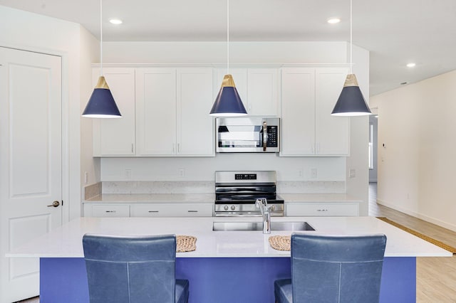 kitchen featuring pendant lighting, a center island with sink, and stainless steel appliances