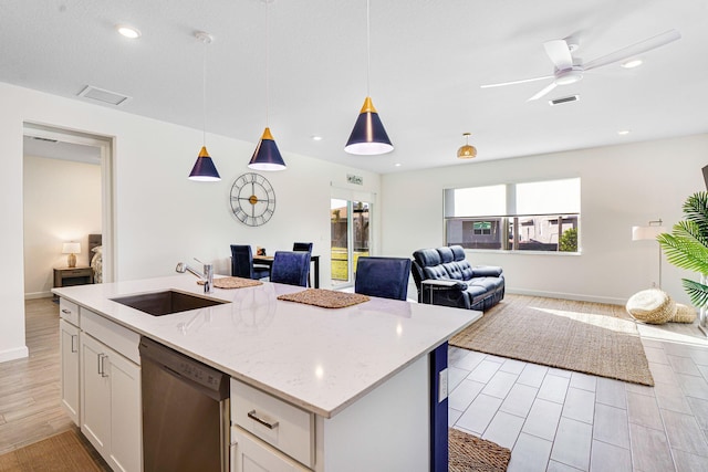 kitchen featuring dishwasher, a kitchen island with sink, white cabinets, sink, and hanging light fixtures