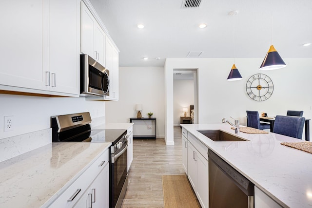 kitchen with white cabinets, decorative light fixtures, stainless steel appliances, and sink