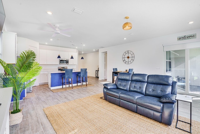 living room with ceiling fan and light wood-type flooring