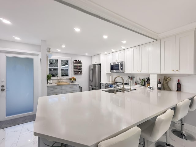 kitchen featuring a kitchen breakfast bar, sink, kitchen peninsula, white cabinetry, and stainless steel appliances