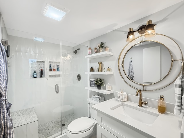 bathroom featuring vanity, a shower with shower door, and toilet