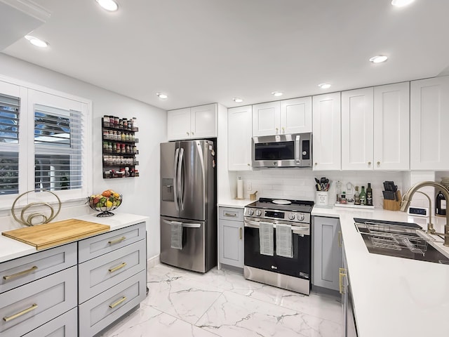 kitchen featuring gray cabinetry, backsplash, sink, appliances with stainless steel finishes, and white cabinetry