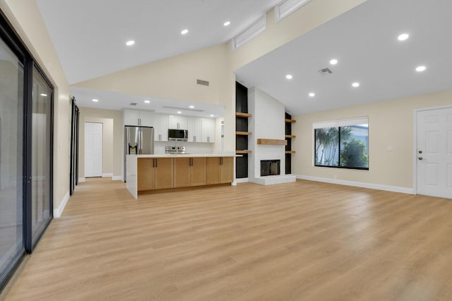 unfurnished living room featuring a fireplace, high vaulted ceiling, and light hardwood / wood-style flooring