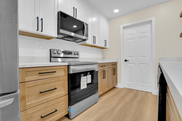 kitchen with white cabinets, light brown cabinetry, tasteful backsplash, light hardwood / wood-style floors, and stainless steel appliances