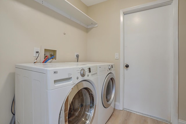 laundry room featuring washer and clothes dryer and light hardwood / wood-style flooring