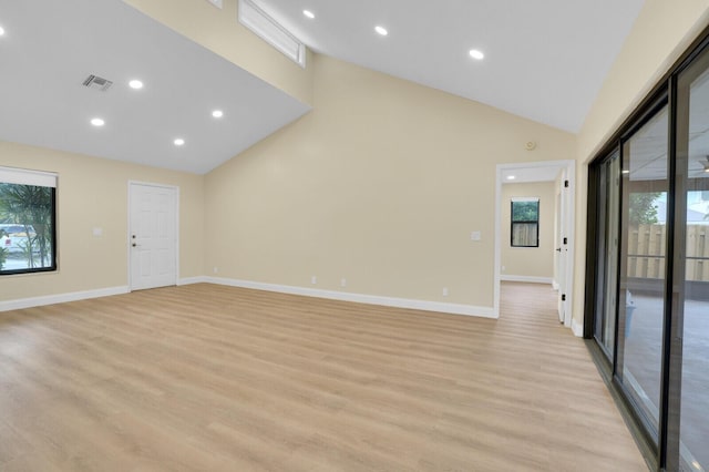 empty room featuring light wood-type flooring and high vaulted ceiling