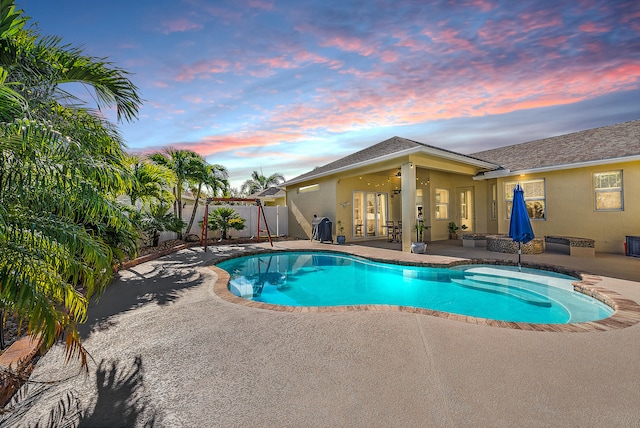 pool at dusk with a patio and ceiling fan